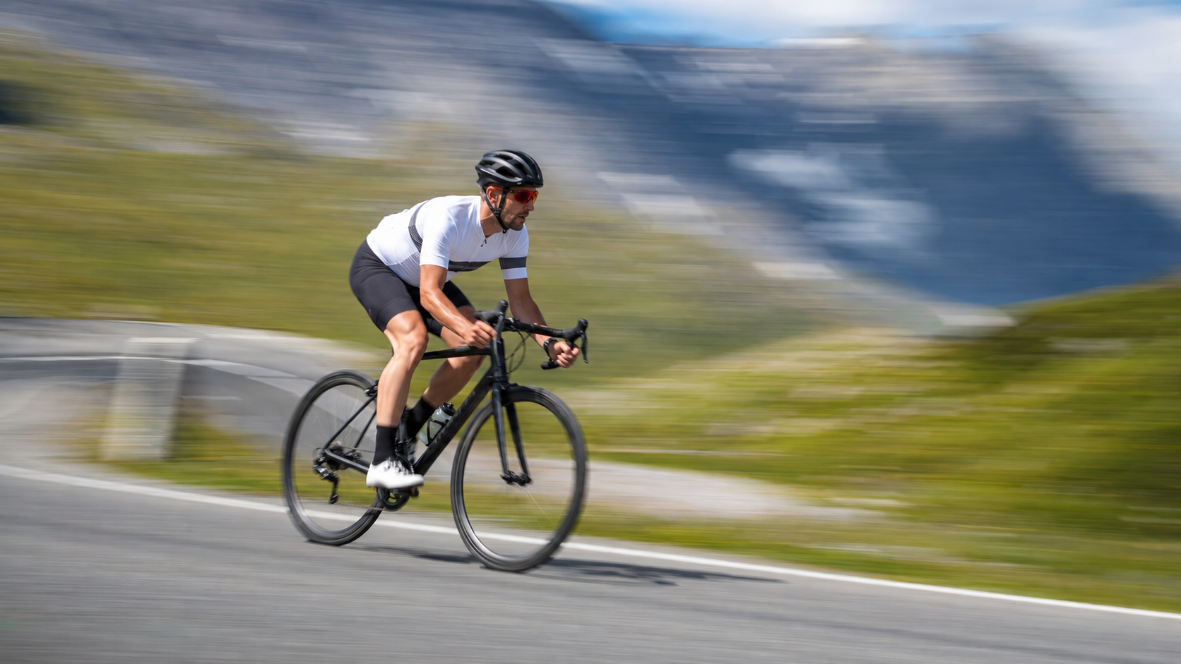 Scharfer Velofahrer vor horizontal verwischter Berglandschaft