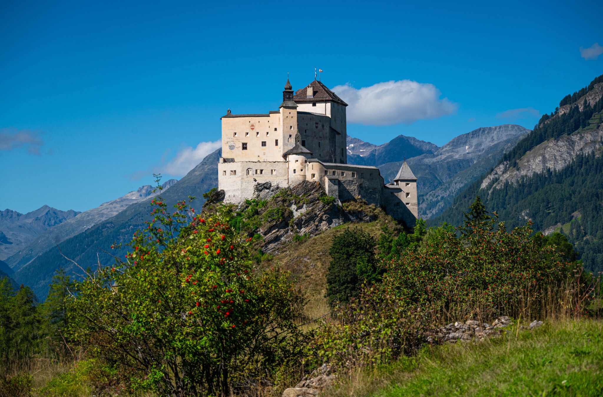 Schloss Tarasp auf einem steilen Felsen vor der Bündner Berglandschaft